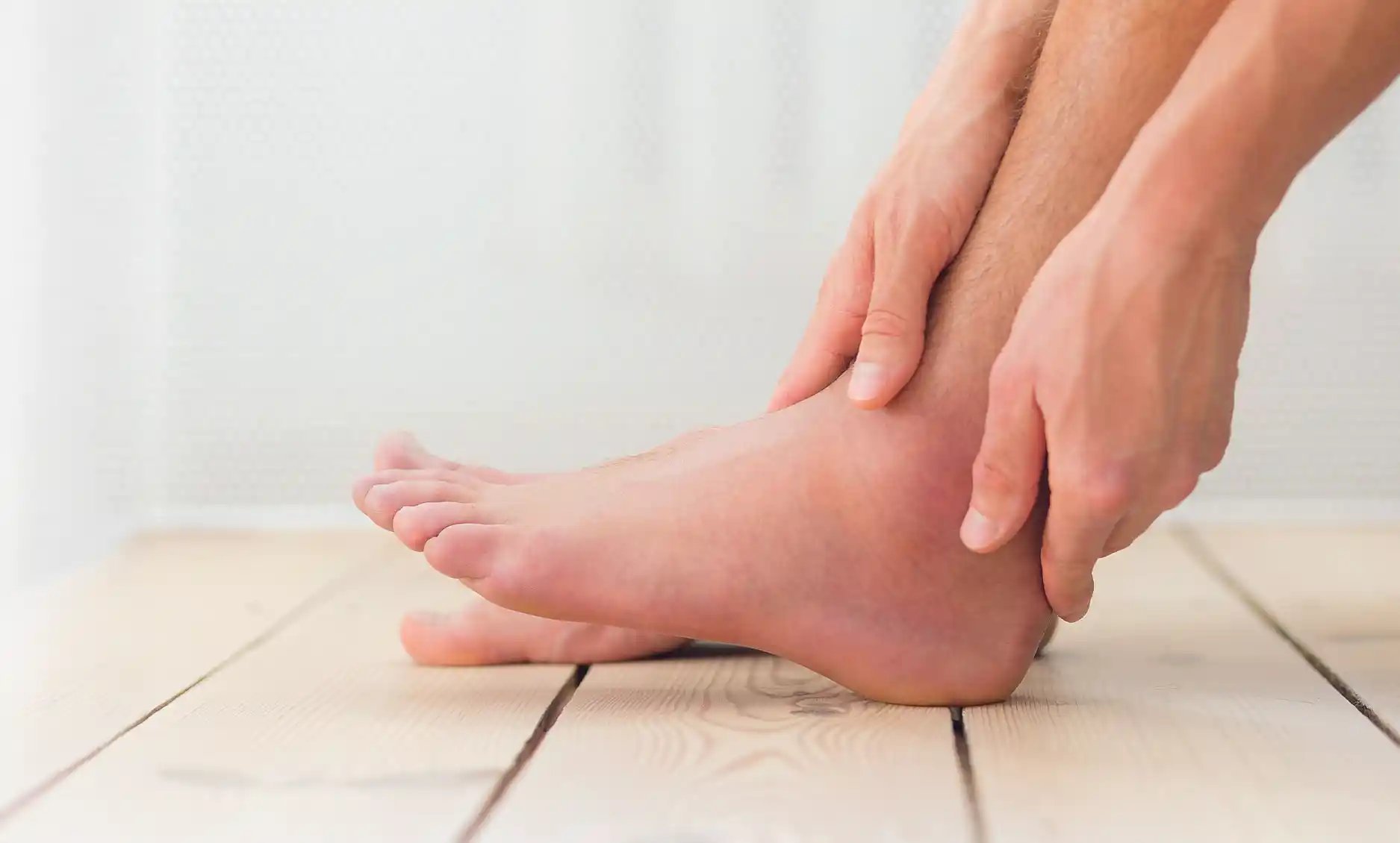 Patient gently holds their ankle, indicating discomfort, highlighting the importance of specialized foot care at Foot & Ankle Center of Arizona.